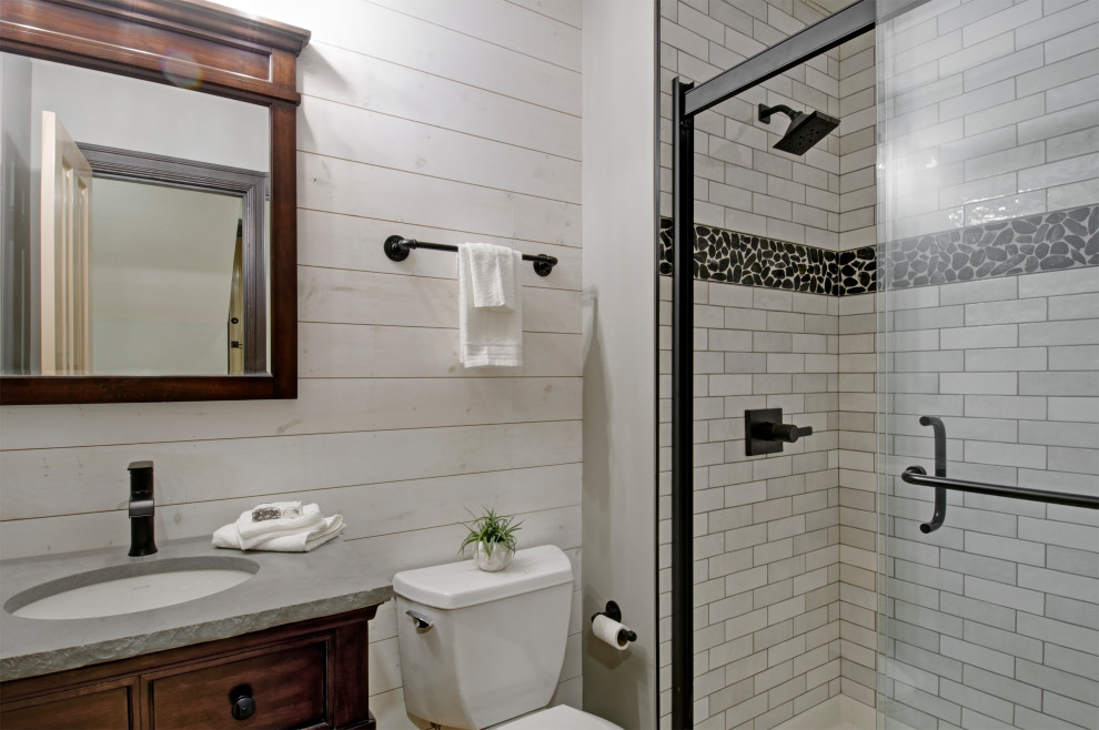 Photo of a large country 3/4 bathroom in Columbus with furniture-like cabinets, medium wood cabinets, an alcove shower, gray tile, subway tile, white walls, bamboo floors, an undermount sink, quartzite benchtops, beige floor, a sliding shower screen and grey benchtops.