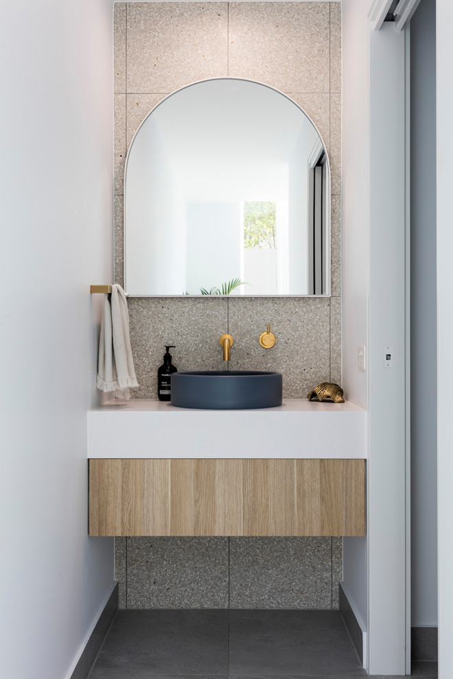 Design ideas for a contemporary powder room in Sunshine Coast with flat-panel cabinets, light wood cabinets, gray tile, white walls, a vessel sink, grey floor and white benchtops.