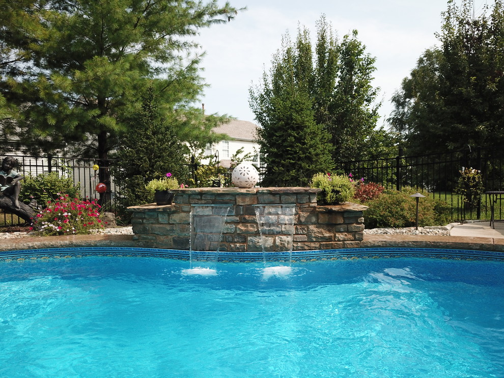 Photo of a mid-sized contemporary backyard custom-shaped pool in St Louis with a water feature and stamped concrete.