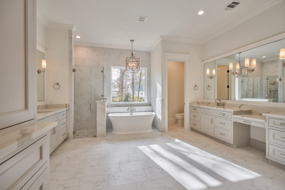This is an example of a large master bathroom in Houston with recessed-panel cabinets, grey cabinets, a freestanding tub, a corner shower, a one-piece toilet, white walls, pebble tile floors, an undermount sink, grey floor, a hinged shower door, grey benchtops, an enclosed toilet, a double vanity and a built-in vanity.