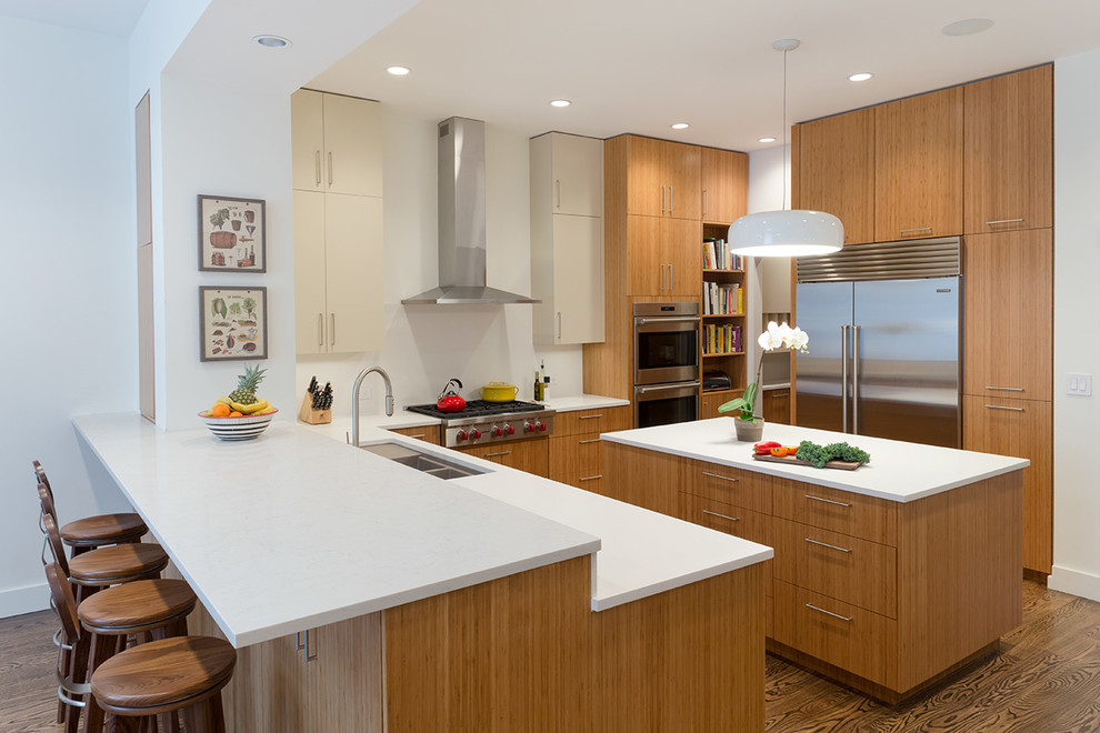 Design ideas for a mid-sized contemporary l-shaped eat-in kitchen in New York with an undermount sink, flat-panel cabinets, medium wood cabinets, quartz benchtops, white splashback, stainless steel appliances, medium hardwood floors and with island.