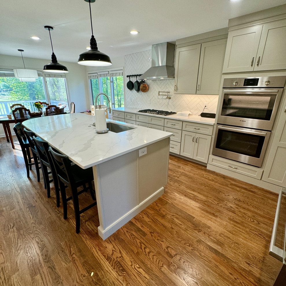 Inspiration for a mid-sized transitional l-shaped medium tone wood floor, brown floor and wallpaper ceiling eat-in kitchen remodel in Atlanta with an undermount sink, shaker cabinets, white cabinets, granite countertops, white backsplash, stainless steel appliances, an island and white countertops