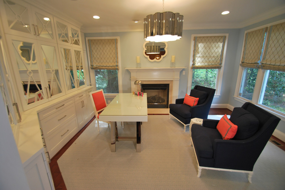 This is an example of a mid-sized modern study room in DC Metro with blue walls, medium hardwood floors, a standard fireplace, a wood fireplace surround, a freestanding desk and brown floor.
