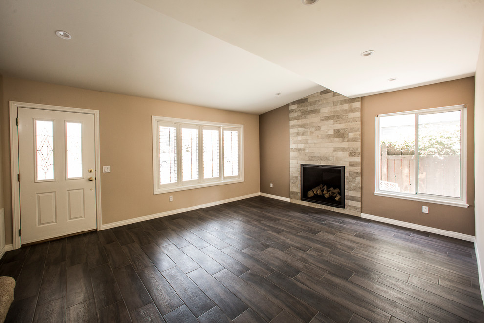 This is an example of a mid-sized transitional formal open concept living room in Orange County with beige walls, dark hardwood floors, a standard fireplace, a stone fireplace surround and brown floor.