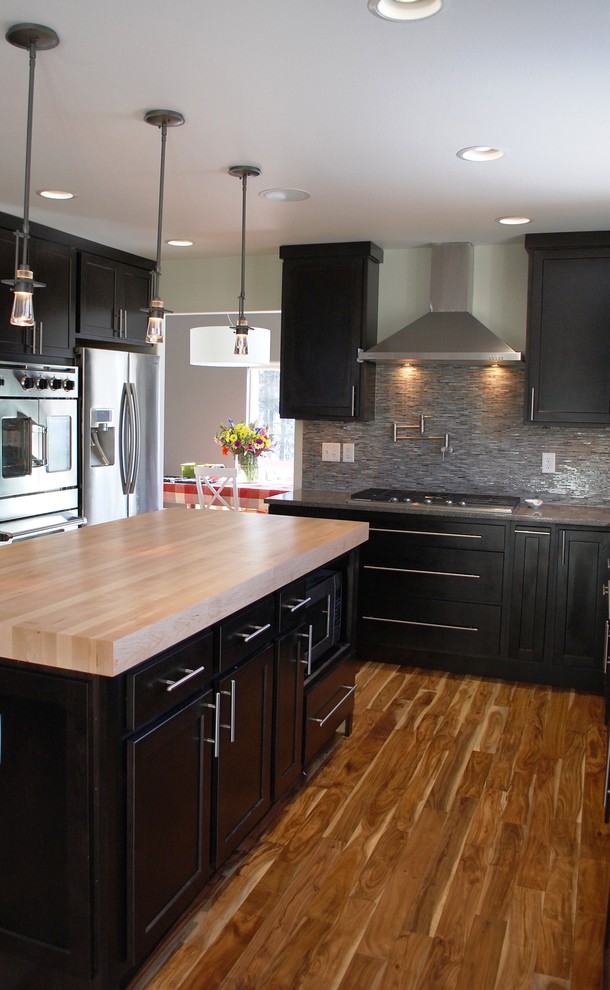 Inspiration for a mid-sized transitional l-shaped light wood floor and brown floor eat-in kitchen remodel with an undermount sink, shaker cabinets, quartz countertops, metallic backsplash, glass tile backsplash, stainless steel appliances, an island and dark wood cabinets