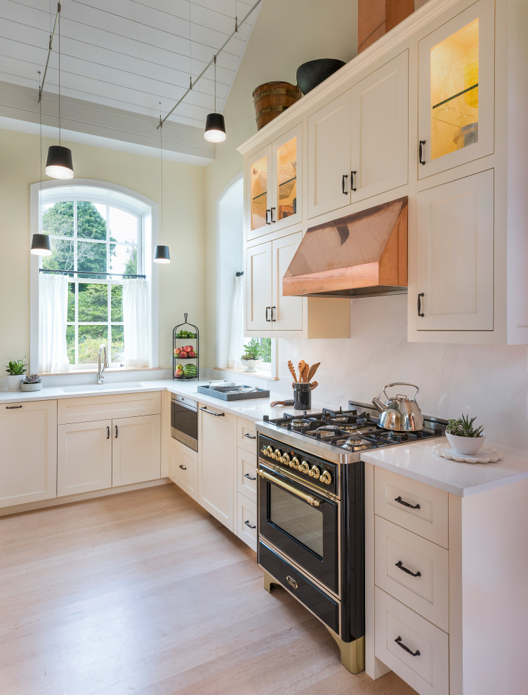 Design ideas for a small transitional l-shaped kitchen in Other with white cabinets, quartz benchtops, no island, an undermount sink, shaker cabinets, white splashback, stone slab splashback, black appliances, light hardwood floors, beige floor and white benchtop.