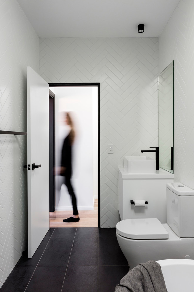 Design ideas for a mid-sized contemporary 3/4 wet room bathroom in Sydney with flat-panel cabinets, white cabinets, a freestanding tub, a wall-mount toilet, white tile, ceramic tile, white walls, ceramic floors, a vessel sink, engineered quartz benchtops, grey floor and an open shower.
