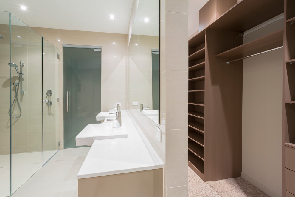 Inspiration for a large contemporary master bathroom in Melbourne with open cabinets, an open shower, a one-piece toilet, porcelain tile, porcelain floors, solid surface benchtops, an open shower, light wood cabinets, beige tile, beige walls, a drop-in sink and beige floor.