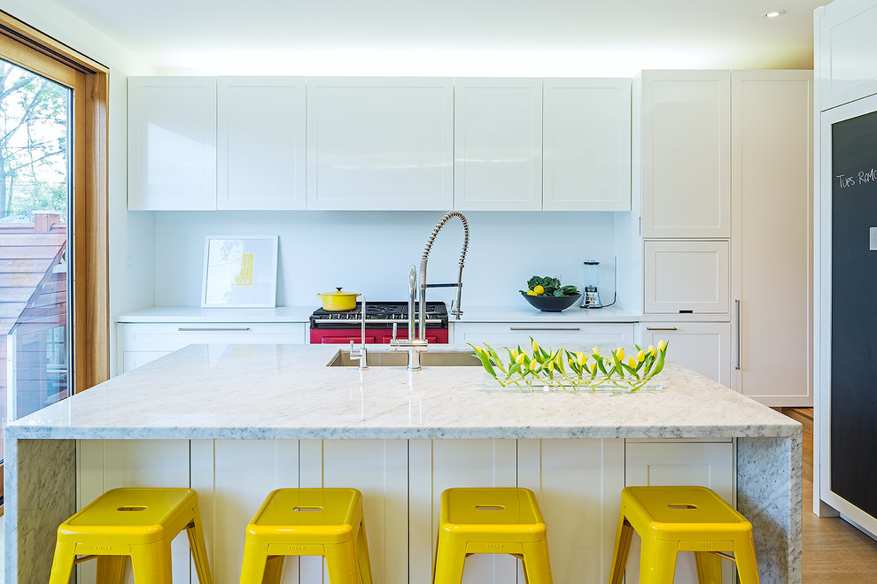 Photo of a contemporary kitchen in Toronto with shaker cabinets, white cabinets, marble benchtops, white splashback, panelled appliances, medium hardwood floors and with island.
