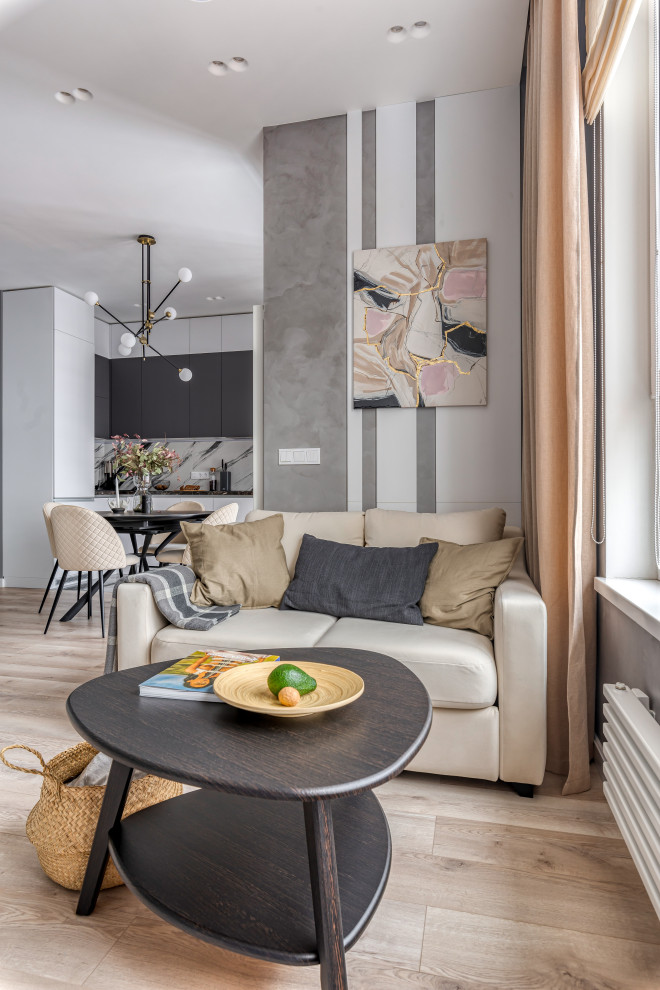 На фото: большая серо-белая гостиная комната:: освещение в скандинавском стиле с серыми стенами, светлым паркетным полом, телевизором на стене и зоной отдыха