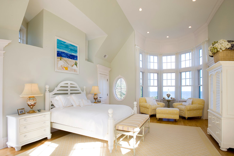 This is an example of a beach style master bedroom in Boston with green walls and medium hardwood floors.