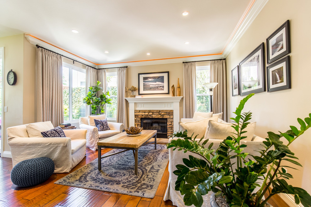 This is an example of a mid-sized transitional open concept family room in Orange County with beige walls, dark hardwood floors, a standard fireplace, a stone fireplace surround and a built-in media wall.