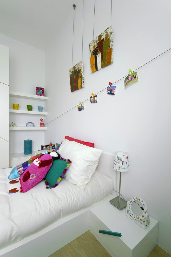 This is an example of a contemporary kids' bedroom for kids 4-10 years old and girls in Other with white walls and light hardwood floors.