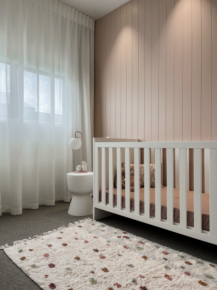 Ejemplo de habitación de bebé niña actual de tamaño medio con paredes rosas, moqueta, suelo gris y boiserie