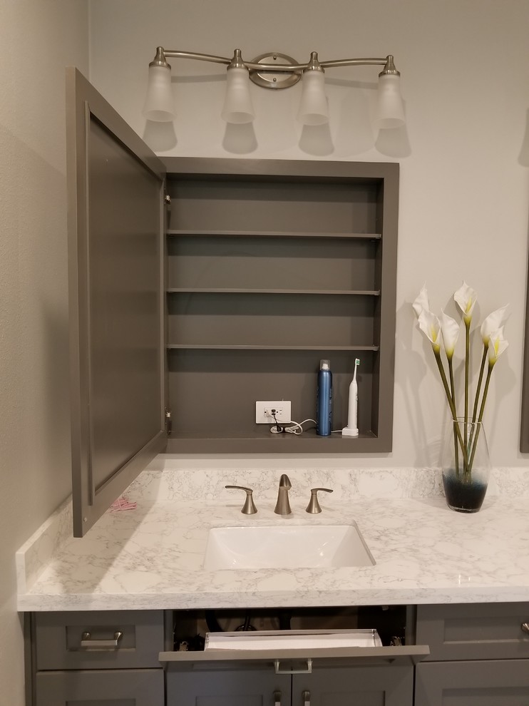 Photo of a large modern master bathroom in Houston with shaker cabinets, grey cabinets, a drop-in tub, a shower/bathtub combo, a one-piece toilet, gray tile, porcelain tile, grey walls, porcelain floors, an undermount sink, engineered quartz benchtops, beige floor and a hinged shower door.