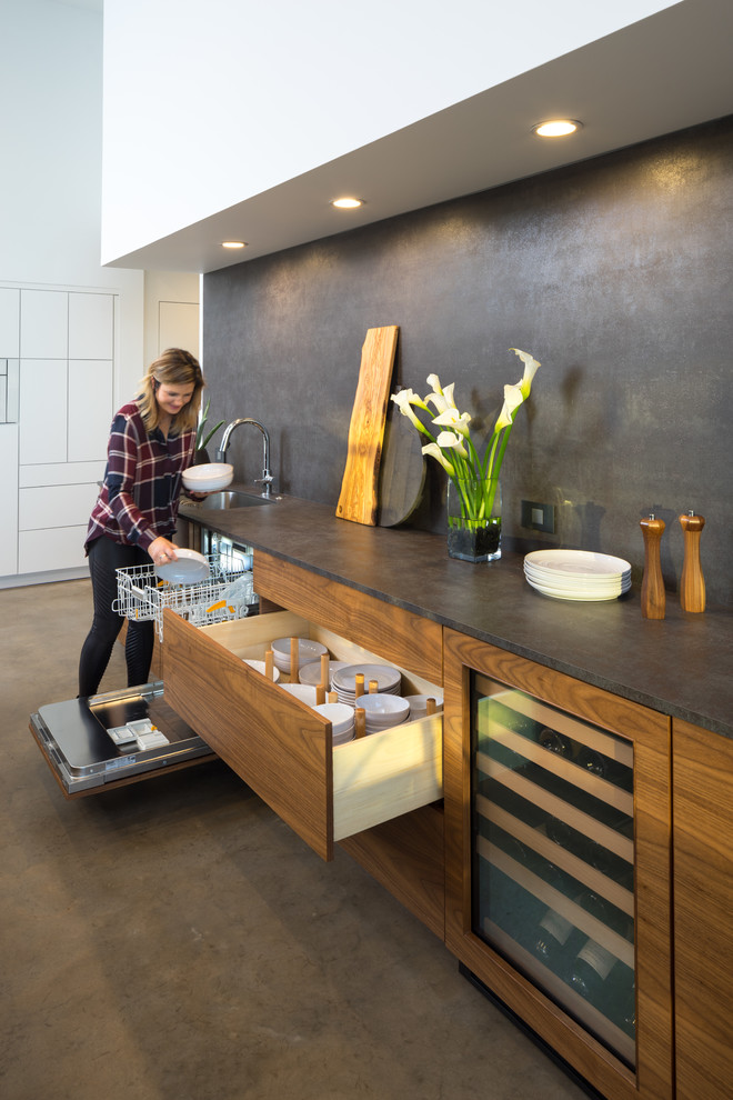 Mid-sized modern l-shaped open plan kitchen in Oklahoma City with an undermount sink, flat-panel cabinets, quartz benchtops, black splashback, white appliances, concrete floors and with island.