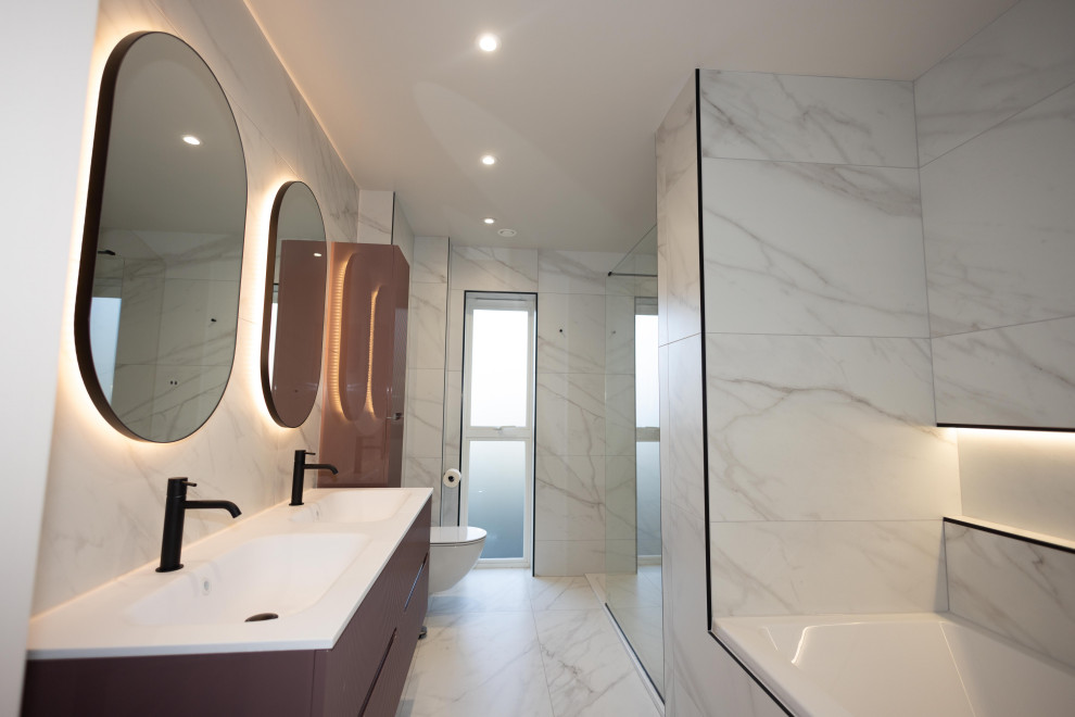 Idée de décoration pour une salle de bain minimaliste avec un placard à porte plane, des portes de placard violettes, un carrelage blanc, du carrelage en marbre, meuble double vasque et meuble-lavabo suspendu.