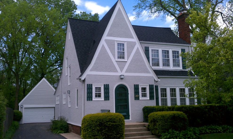 Mid-sized traditional two-storey stucco grey house exterior in Chicago with a gable roof and a shingle roof.