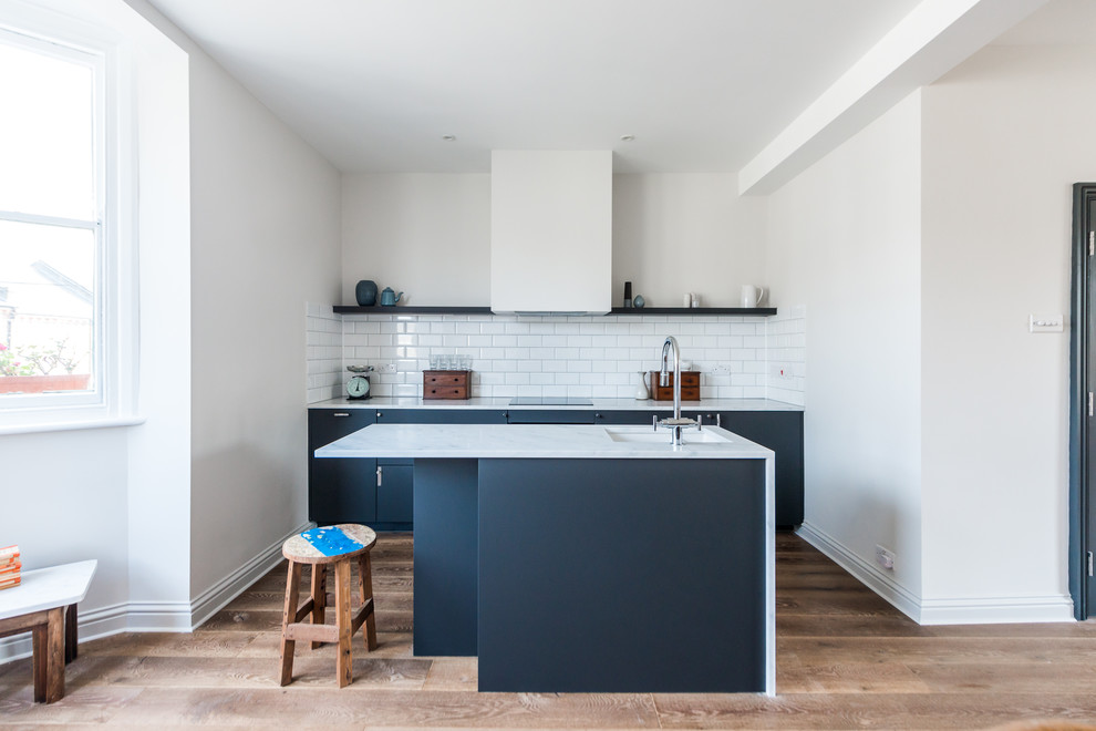 Design ideas for a small scandinavian u-shaped open plan kitchen in London with a drop-in sink, recessed-panel cabinets, black cabinets, marble benchtops, white splashback, cement tile splashback, stainless steel appliances, dark hardwood floors and with island.