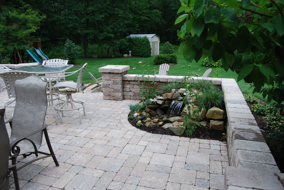 Design ideas for a mid-sized transitional backyard patio in Other with a water feature, brick pavers and no cover.