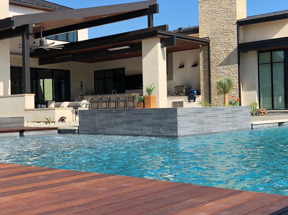 Inspiration for a large contemporary backyard l-shaped pool in Dallas with concrete slab.