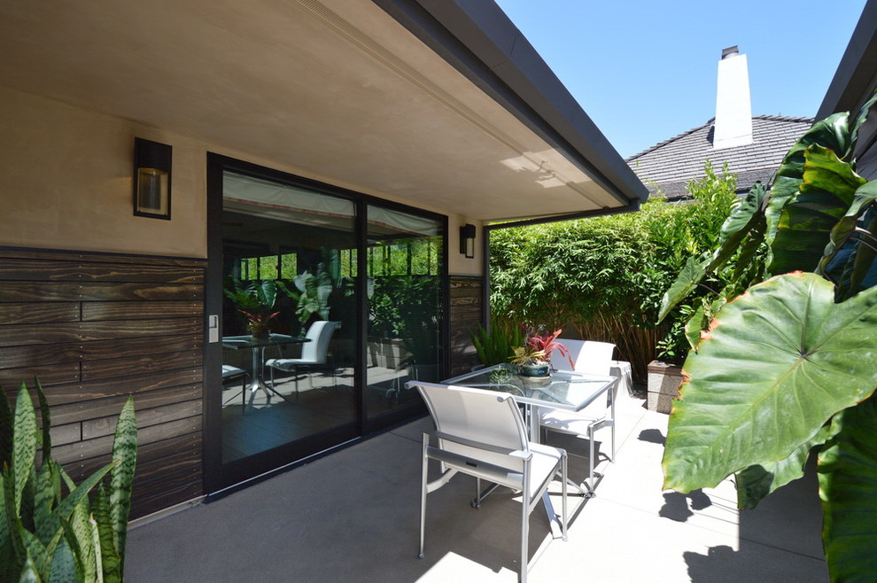This is an example of a large midcentury side yard patio in Los Angeles with concrete slab and a roof extension.