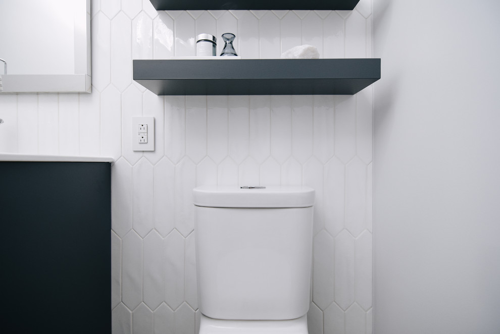 Photo of a small contemporary powder room in Montreal with blue cabinets, a two-piece toilet, white tile, ceramic tile, grey walls, flat-panel cabinets, porcelain floors, an integrated sink, engineered quartz benchtops, grey floor and white benchtops.
