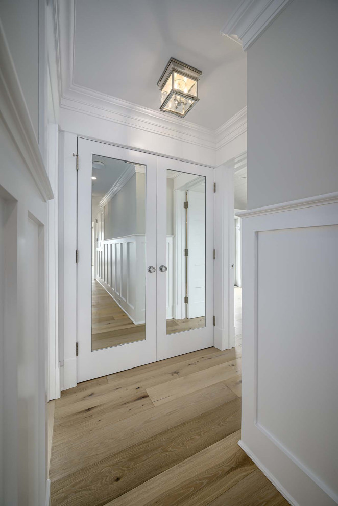 This is an example of a hallway in Philadelphia with beige walls, light hardwood floors, brown floor, wood and decorative wall panelling.