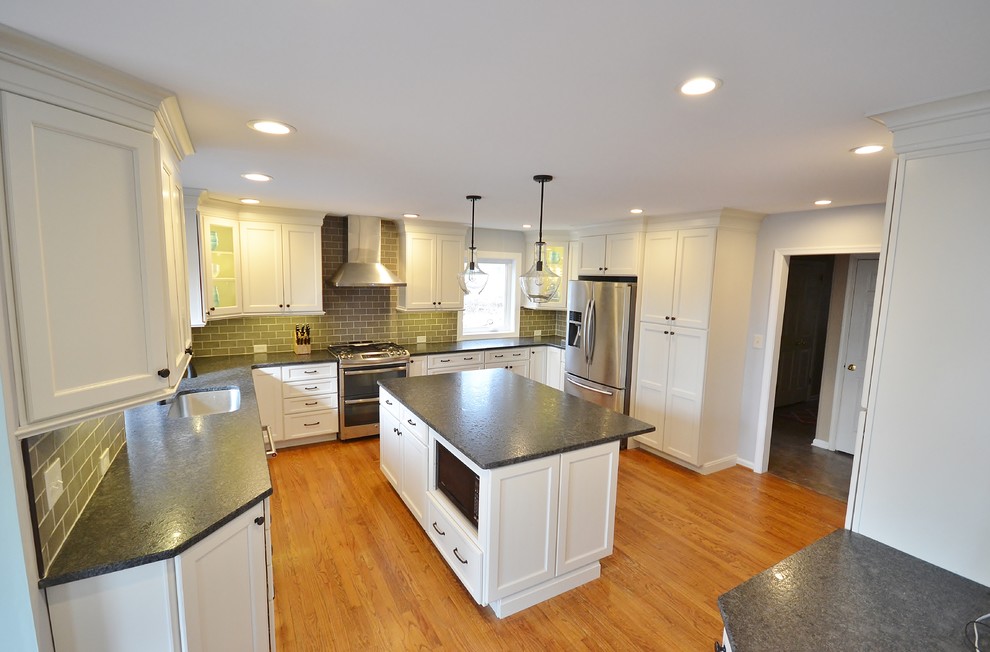 Photo of a large transitional l-shaped eat-in kitchen in Philadelphia with an undermount sink, raised-panel cabinets, white cabinets, granite benchtops, grey splashback, subway tile splashback, stainless steel appliances, medium hardwood floors and with island.
