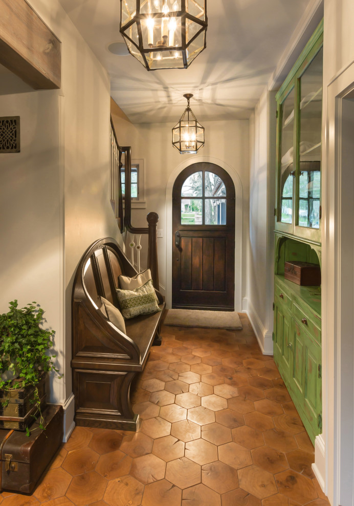 Design ideas for an eclectic foyer in Milwaukee with white walls, terra-cotta floors, a single front door and a dark wood front door.