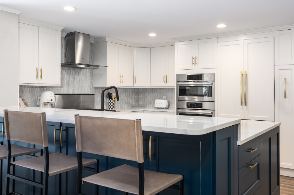This is an example of a mid-sized contemporary u-shaped eat-in kitchen in Boston with a farmhouse sink, recessed-panel cabinets, white cabinets, quartz benchtops, grey splashback, ceramic splashback, stainless steel appliances and white benchtop.