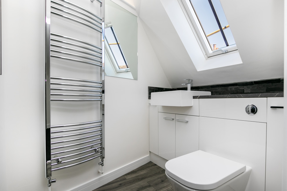 Photo of a small contemporary master bathroom in Oxfordshire with flat-panel cabinets, white cabinets, an alcove shower, a one-piece toilet, gray tile, white walls, vinyl floors, a wall-mount sink, laminate benchtops, grey floor, a niche, a single vanity, a built-in vanity and vaulted.