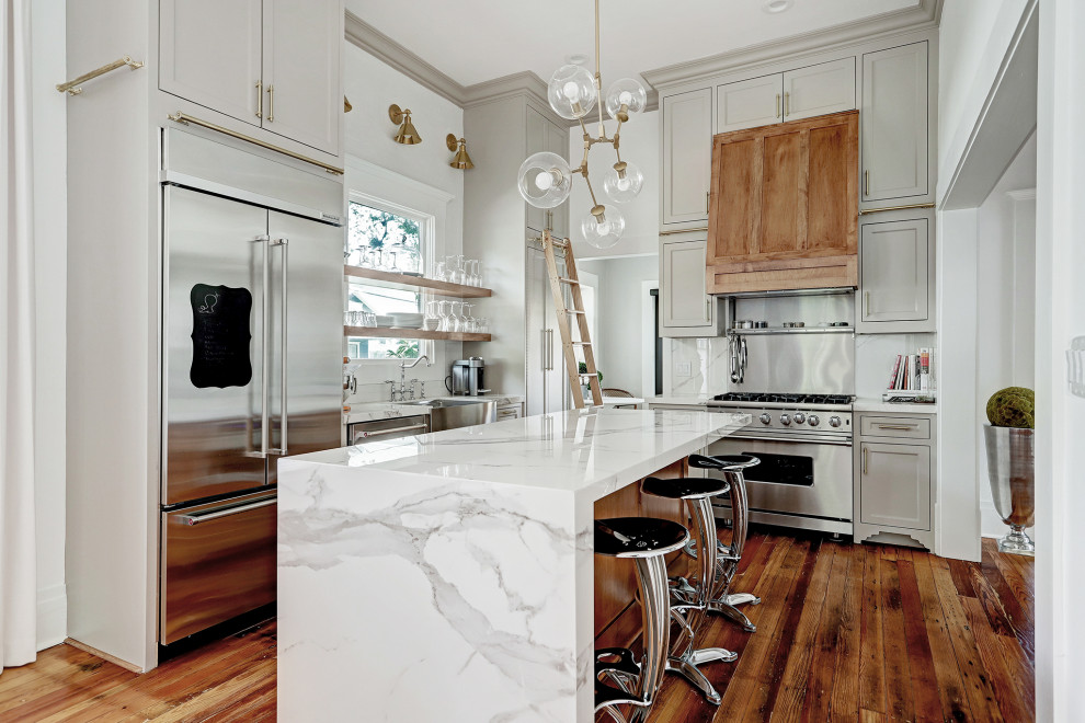 Example of a transitional u-shaped medium tone wood floor and brown floor eat-in kitchen design in Houston with a farmhouse sink, shaker cabinets, gray cabinets, marble countertops, multicolored backsplash, marble backsplash, stainless steel appliances, an island and multicolored countertops