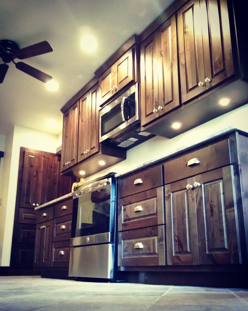 Mid-sized mountain style galley slate floor and beige floor eat-in kitchen photo with raised-panel cabinets, dark wood cabinets, granite countertops, an undermount sink, stainless steel appliances and no island