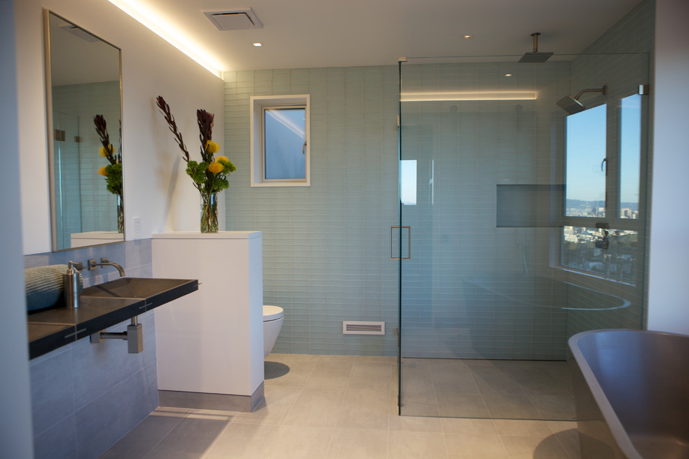 Large transitional master bathroom in San Francisco with glass-front cabinets, a freestanding tub, a curbless shower, a wall-mount toilet, green tile, glass tile, white walls, ceramic floors, a wall-mount sink, granite benchtops, grey floor and a hinged shower door.