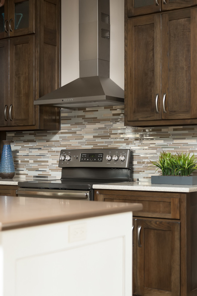 Mid-sized transitional l-shaped vinyl floor eat-in kitchen photo with stainless steel appliances, a farmhouse sink, shaker cabinets, dark wood cabinets, quartz countertops, multicolored backsplash, matchstick tile backsplash and an island