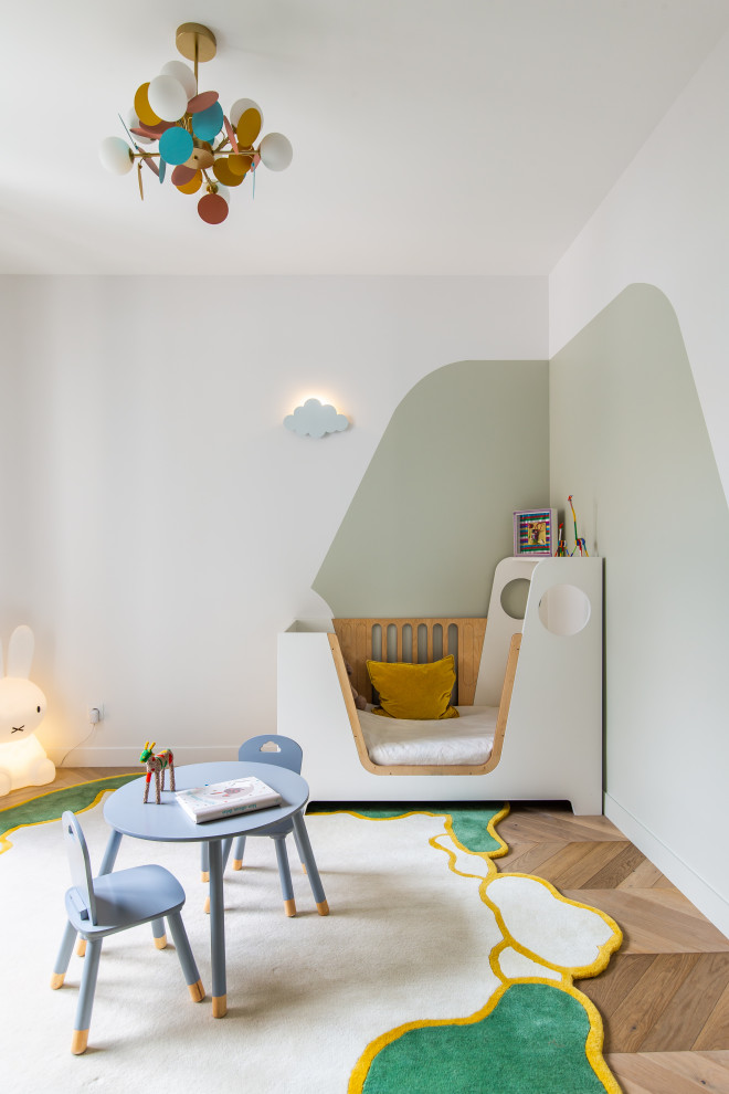 Bild på ett funkis könsneutralt småbarnsrum kombinerat med sovrum, med vita väggar, mellanmörkt trägolv och brunt golv