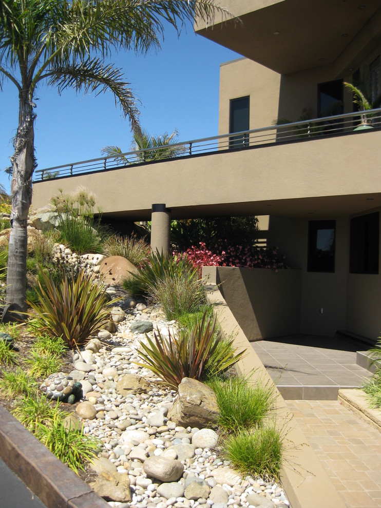 Photo of a contemporary sloped garden in San Luis Obispo with with rock feature and river rock.