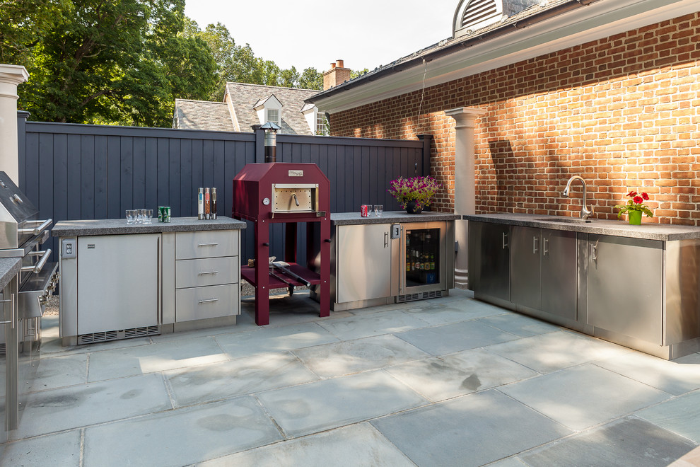 This is an example of a mid-sized contemporary backyard patio in New York with natural stone pavers, a pergola and an outdoor kitchen.