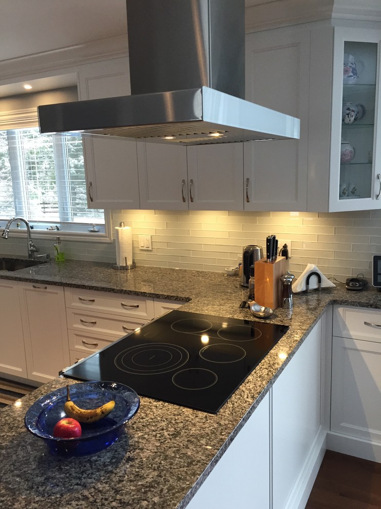 Inspiration for a mid-sized transitional single-wall dark wood floor and brown floor eat-in kitchen remodel in Montreal with an undermount sink, recessed-panel cabinets, white cabinets, quartz countertops, white backsplash, glass tile backsplash, white appliances and a peninsula