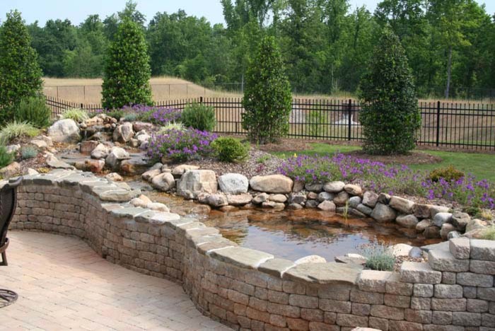 Photo of a mid-sized full sun brick water fountain landscape in Charlotte.