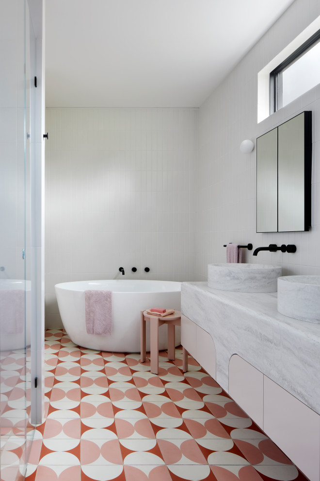 メルボルンにあるラグジュアリーな広いコンテンポラリースタイルのおしゃれな浴室 (置き型浴槽、白いタイル、ピンクの床、グレーの洗面カウンター、洗面台2つ、独立型洗面台) の写真