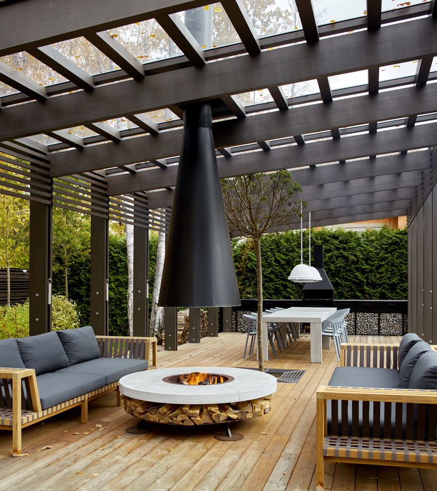 This is an example of a contemporary patio in Moscow with decking, a pergola and with fireplace.