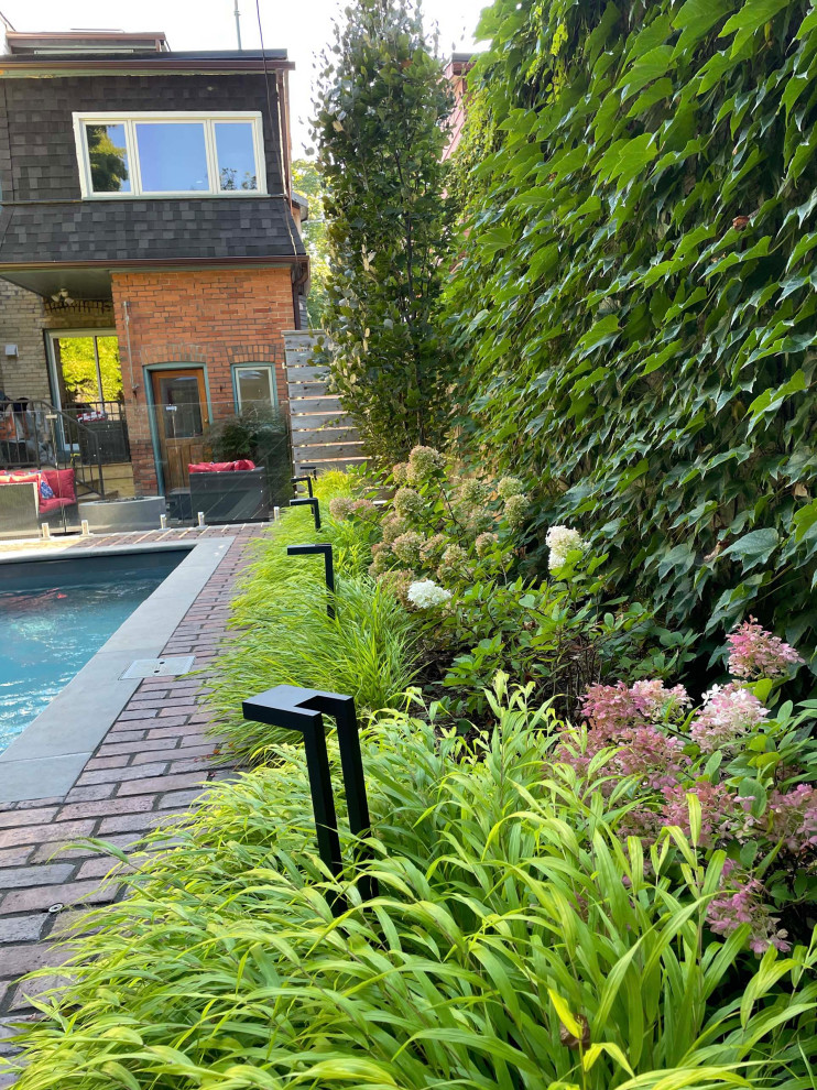 Photo of a mid-sized eclectic full sun backyard concrete paver and wood fence flower bed in Toronto.
