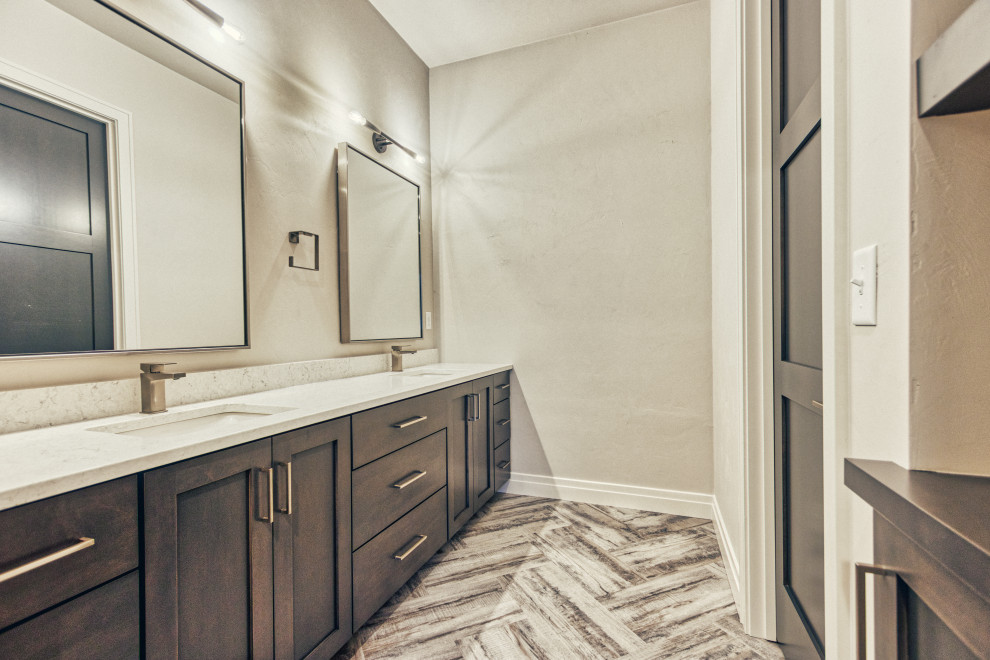 Example of a large transitional 3/4 vinyl floor and multicolored floor tub/shower combo design with shaker cabinets, gray cabinets, a two-piece toilet, gray walls, an undermount sink, quartz countertops and white countertops