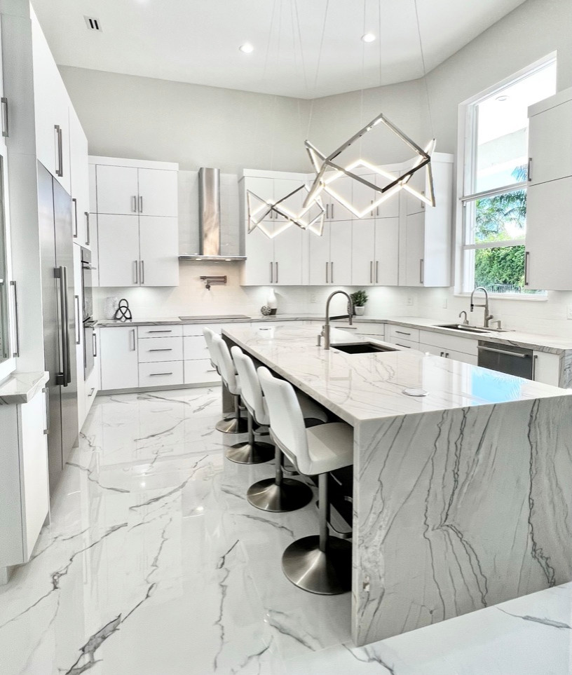 Large modern kitchen in Miami with a single-bowl sink, flat-panel cabinets, white cabinets, quartzite benchtops, white splashback, porcelain splashback, stainless steel appliances, porcelain floors, with island, white floor and grey benchtop.