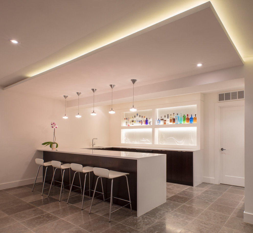This is an example of a modern home bar in DC Metro with porcelain floors, an undermount sink, flat-panel cabinets, dark wood cabinets, solid surface benchtops, white splashback, glass sheet splashback and white benchtop.