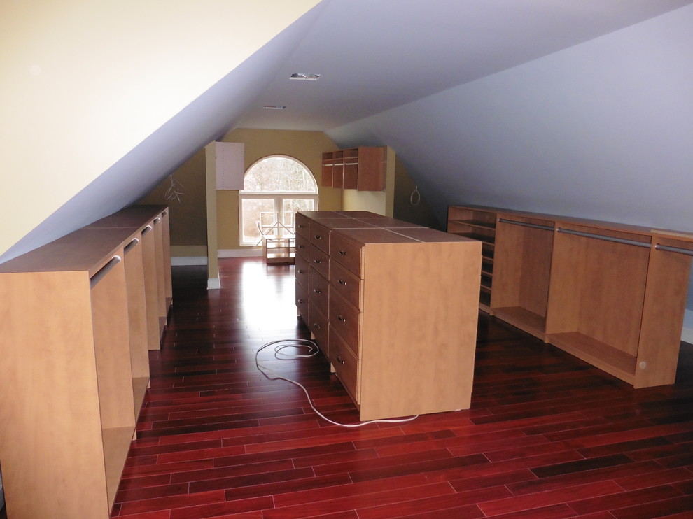 This is an example of a mid-sized gender-neutral walk-in wardrobe in New York with open cabinets, medium wood cabinets and medium hardwood floors.