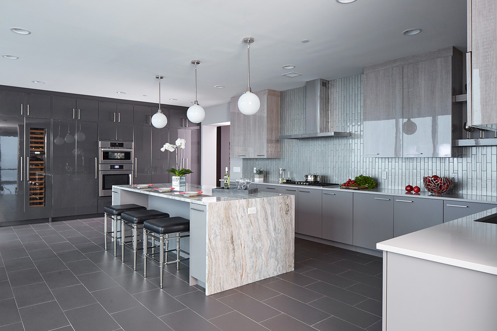 Expansive contemporary u-shaped eat-in kitchen in New York with an undermount sink, flat-panel cabinets, grey cabinets, quartz benchtops, grey splashback, glass tile splashback, stainless steel appliances, porcelain floors, with island, grey floor and multi-coloured benchtop.