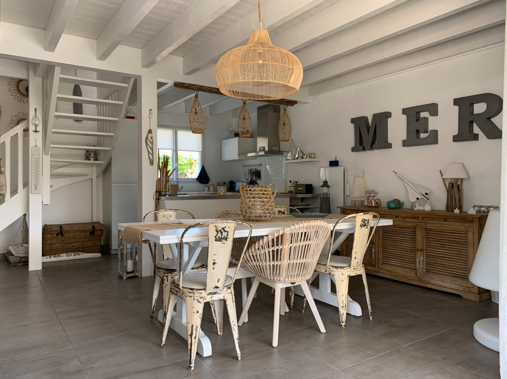 Cette image montre une salle à manger ouverte sur le salon marine de taille moyenne avec un mur blanc, aucune cheminée, un sol gris et un plafond en bois.